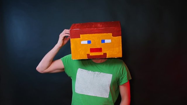 Hero of the electronic game in the drawn mask scratches his head with his hand.