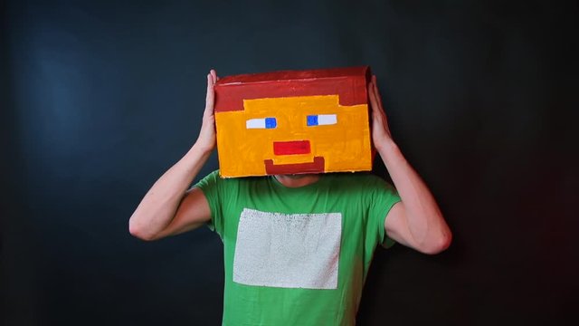 A man brings his hands to a drawn mask on his head.