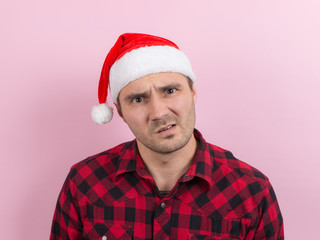 Emotions on the face, indifference and disgust. A man in a plaid rabbit and a Christmas red hat, on...