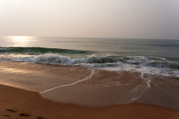 very beautiful sunrise on the sea beach with sea water waves and foam under sky in India,sand beach with wave background, Vacation Travel and Holiday concept, sunrise, footsteps on sand