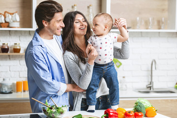 Young parents playing with baby son on kitchen table