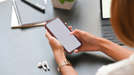 Closeup female using mockup smartphone on office workspace.