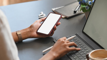 Closeup female using mockup smartphone on office workspace.