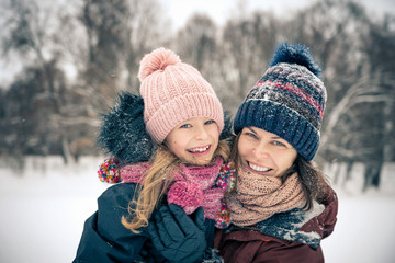 Fototapeta premium Mała dziewczynka i jej matka, grając na zewnątrz w zimowy dzień. Koncepcja aktywnych zimowych wakacji.