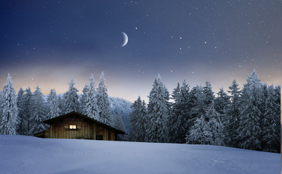 Beleuchtete Holzh&uuml;tte in einer Winternacht