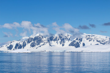 Snow-capped mountains on an island along the coasts of the Antarctic Peninsula, Antarctica