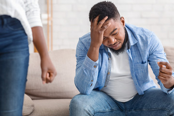 Despaired black guy holding wedding ring while his wife leaving him