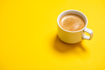 Black coffee in a cup on a yellow background