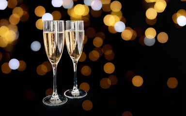 Happy New Year concept, two glasses of champagne on black background with yellow bokeh circles. Merry christmas.