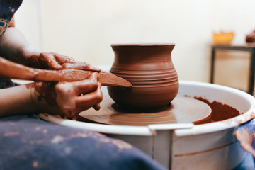 Fototapeta na wymiar Girl works behind a pottery wheel forms a jug to perfect forms