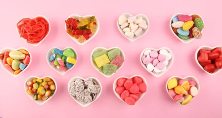 Fotobehang candies with jelly and sugar. colorful array of different childs sweets and treats on pink background © beats_