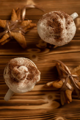 Top view of Christmas creamy hot beverage with star gingerbread cookies on wooden background