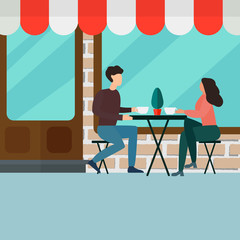 Happy couple sitting and drinking coffee at the table in street cafe.