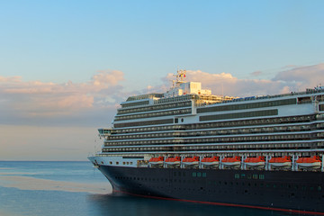 Fototapeta premium Huge luxury cruise ship glides out of the port of Koper during magic sunrise. Colorful vibrant sky. Travel and tourism concept. Koper, Slovenia
