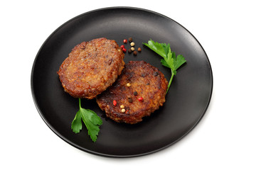 grilled burger meat with spices on black plate isolated on white background