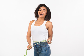 Portrait of happy young black woman measuring waist