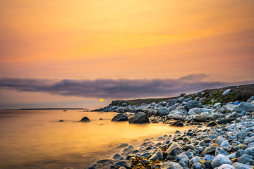 Long exposure sunset seascape of a Nova Scotia beach at dusk.  Beautiful colours are on display to highlight the sand, rocks, seaweed and barnacles.