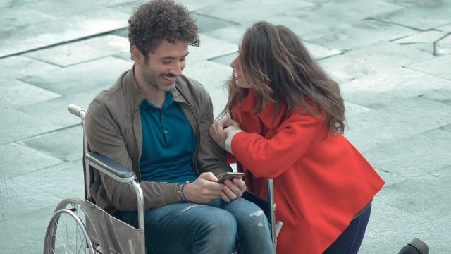 Romatic moment.shy man on wheelchair refusing kiss from young woman