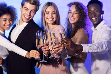 Happy millennials clinking champagne glasses having party standing indoor