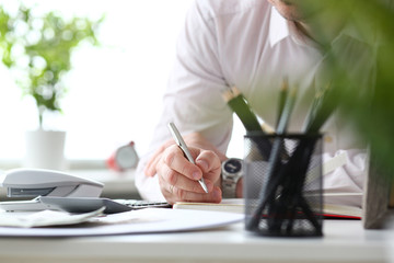 Male clerk hand holding silver pen writing something