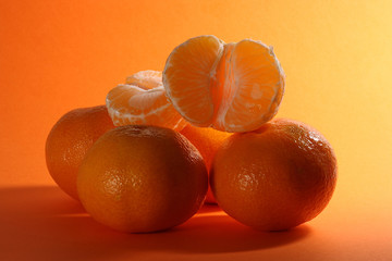 Juicy ripe tangerines on an orange background with a bright shade on the right