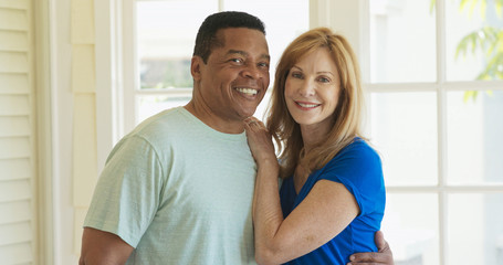Portrait of mixed race senior couple looking at camera and holding each other