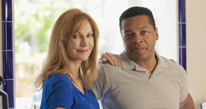 Happy Senior mixed race couple homeowners looking at camera
