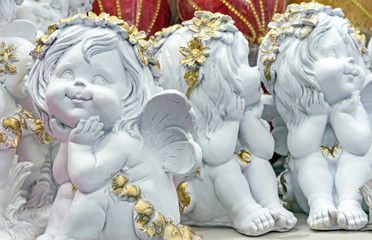 Ceramic figurines of white angels with golden wreaths.