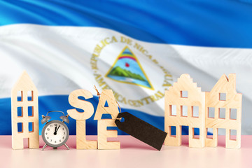 Nicaragua real estate sale concept. Wooden house model with discount tag on national flag background. Copy space for text.