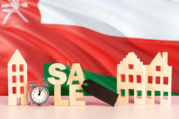 Oman real estate sale concept. Wooden house model with discount tag on national flag background. Copy space for text.