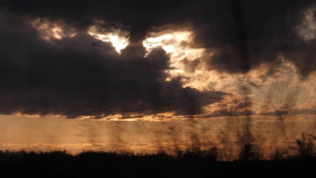 The view from the train window on the landscape passing by. The sky during sunset.