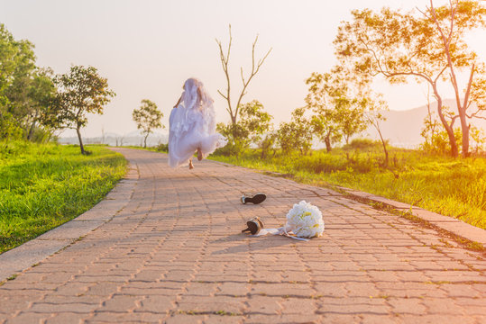 Beautiful bride wearing a white wedding dress running away alone