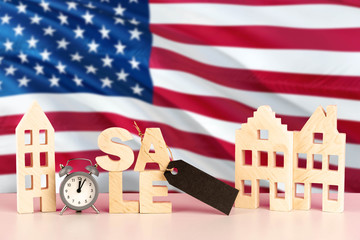 United States real estate sale concept. Wooden house model with discount tag on national flag background. Copy space for text.