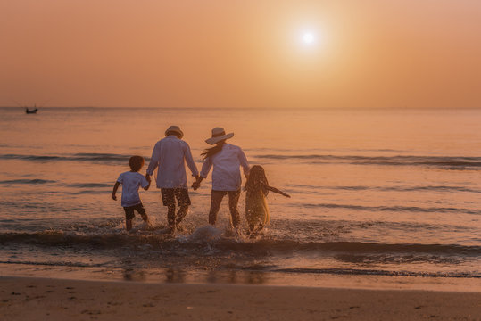 Happy Asian Family At Consisting Father, Mother, Son And Daughter Having Fun On Summer Vacation On The Beach