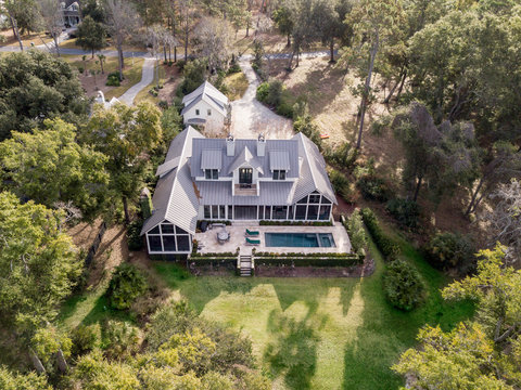 Aerial view of beautiful large home with pool on wooded lot.