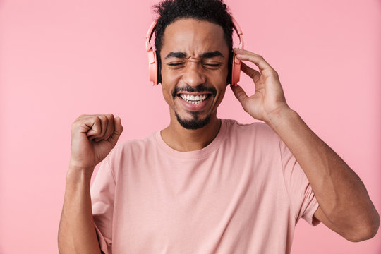 Photo of amazed african american man using headphones and smiling