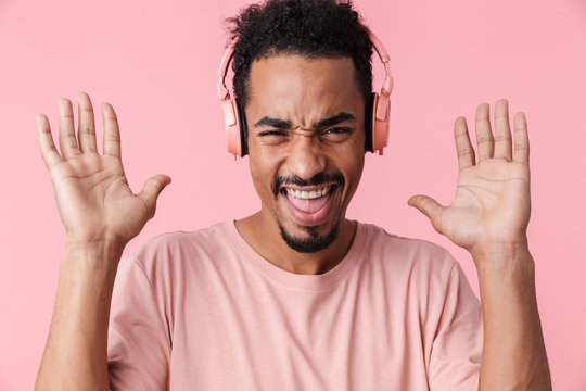 Photo of amazed african american man with hands up using headphones