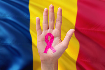 Chad awareness concept. Close-up awareness ribbon painted on palm on national flag background. October Pink day and world cancer day.