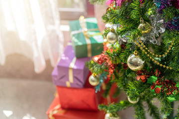 Decorated Christmas tree with stack of present boxes in the background.