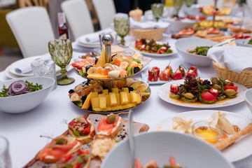 table setting for festive dinner with lot of salads, vegetables and fruit