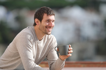 Happy man holding coffee cup contemplating views outdoors