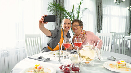 Happy family of women and grandmothers laugh and take a selfie in a cafe restaurant. Time for a selfie.