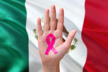 Mexico awareness concept. Close-up awareness ribbon painted on palm on national flag background....