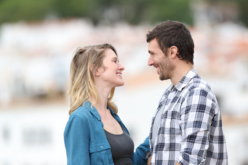 Fototapeta premium Profile of a couple flirting looking each other in a town