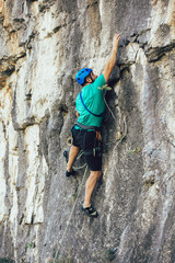 Man with a rope engaged in the sports of rock climbing on the rock.