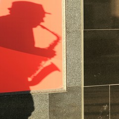 shadow of saxophone player on red background