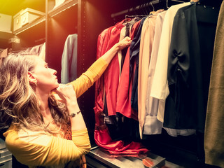 Woman chooses clothes at fashionable shop. side view of mature woman choosing clothes in clothing...
