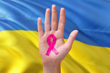 Ukraine awareness concept. Close-up awareness ribbon painted on palm on national flag background. October Pink day and world cancer day.