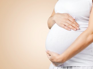 Pregnant young woman in white t shirt on background