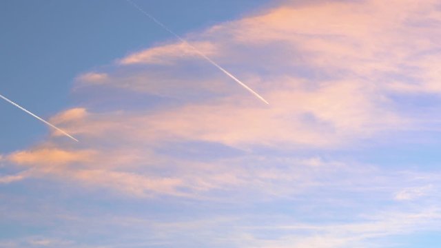 Two planes flying in parallel cross orange clouds in a blue sky during sunset, inspiration for travelers and agencies